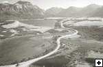 a road winds through an aerial view of Waterton’s prairie, lakes and mountains,  Parks Canada / Ron Garnett