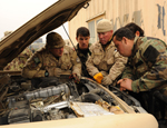 MCpl Chris Cleary (centre) and Cpl Pascal DiRico (left) show a group of ANA vehicle technicians how to test a truck battery at the Kabul Military Training Centre, a massive ANA establishment where more than 270 CF members deployed on Operation ATTENTION work as training advisors and support staff.