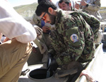 A soldier kneels down as he talks on his radio.