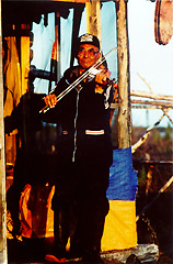 picture of Charlie Peter Charlie Senior playing a fiddle in front of a house