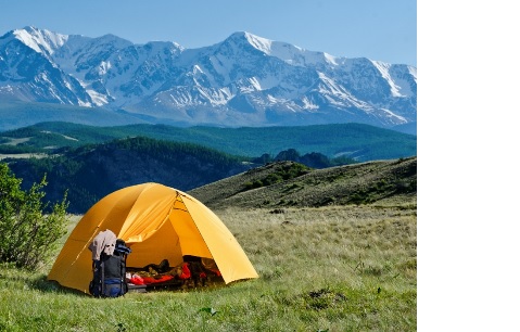 Image: tente dans un champ avec des montagnes en arrière-plan.