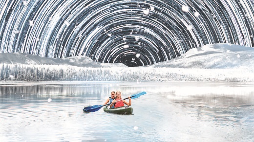 A family kayaks under stars in winter