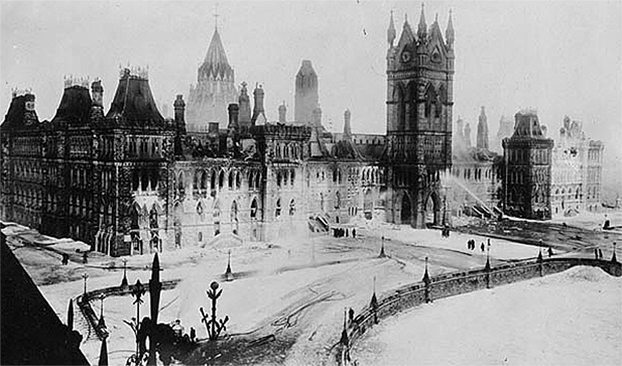 A historical black and white photo of the Centre Block blackened by fire.
