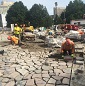 Des travailleurs de la construction placent des pavés de béton en forme de mosaïque.
