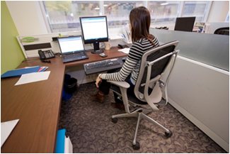 Employee working from a Flexible workstation with ergonomic seating and glass toppers to maximize natural light, Gatineau, QC