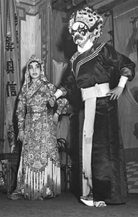 Photographie de deux acteurs chinois en costumes de thtre, sur scne, avec des musiciens assis sur les cts de la scne.