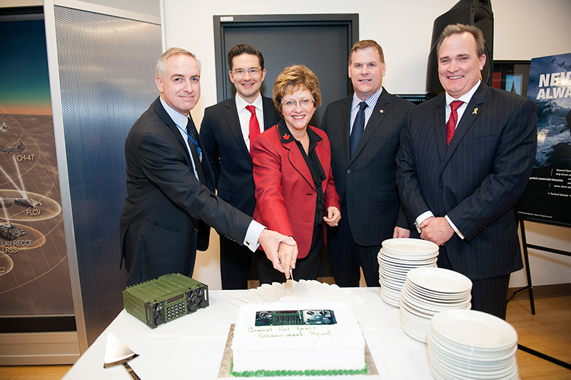 A group of men and a woman cutting a cake.