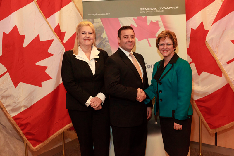 Two people shaking hands while another woman stands beside them.