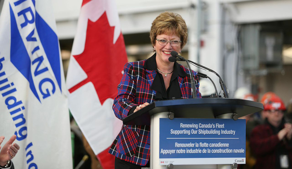 A woman speaking in front of a large group.