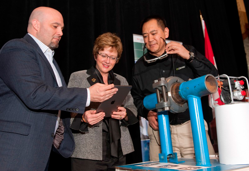 Two men and a woman look at a tablet