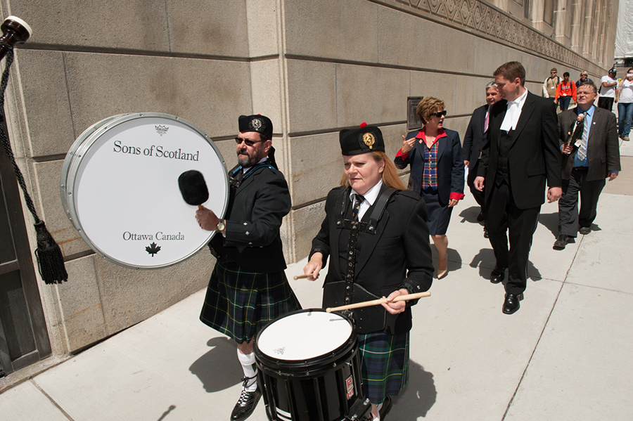 A pipe band, men and women walking.