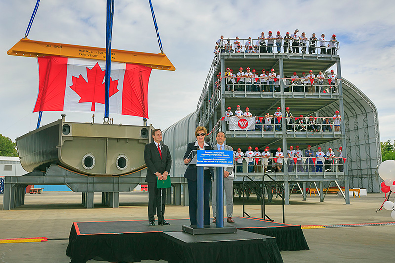 Woman standing behind a podium with two men standing behind her.