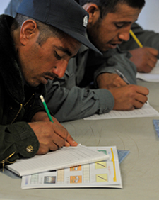Des membres de la Police nationale afghane s'exercent à rédiger lors d'un cours d'alphabétisation coordonné par l'Équipe provinciale de reconstruction de Kandahar.