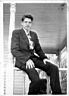 Gaboury as a young man, in suit and tie, sitting on porch railing, 1948
