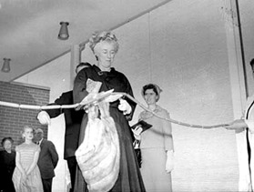 Citizenship and Immigration Minister Ellen Fairclough cuts a ribbon made of wieners for the official opening of F.W. Fearman Company's Burlington, Ontario, plant (April 25, 1962)