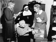 Photo taken on voting day in 1958, one-hundred-year-old Mrs. Ford cast her ballot.  With her are Mrs. Thompson, Sister Constance and Mrs. Carscadden.
