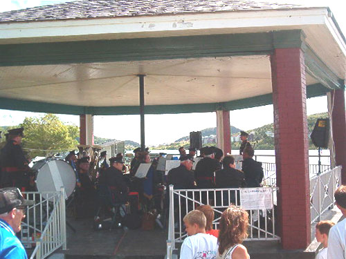 The bandstand full of band members, with several spectators watching nearby