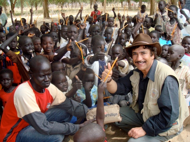 photograph of Ashid Bahl giving pencils and other school supplies to children at a school near Juba, South Sudan